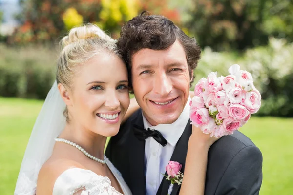 Bruid en bruidegom omarmen en glimlachen op camera — Stockfoto
