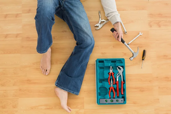 Man lying with several tools on parquet floor — Stock Photo, Image