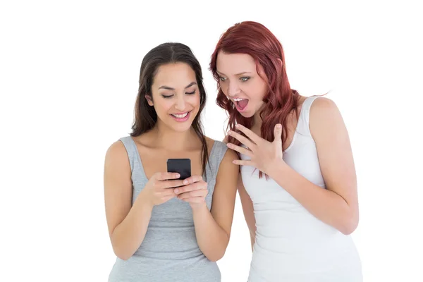 Geschokt jonge vrouwelijke vrienden kijken naar mobiele telefoon — Stockfoto