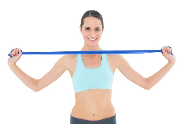 Sonriente en forma joven mujer sosteniendo cinturón de yoga azul — Foto de Stock