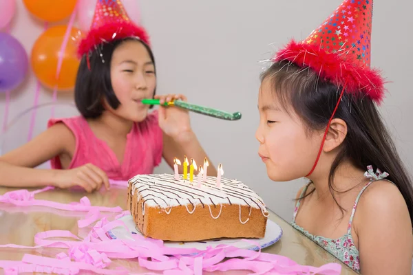 Girls blowing noisemaker and birthday candles — Stock Photo, Image