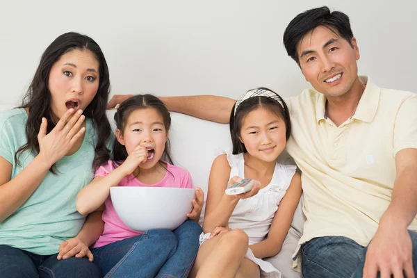 Família feliz de quatro assistindo tv na sala de estar — Fotografia de Stock