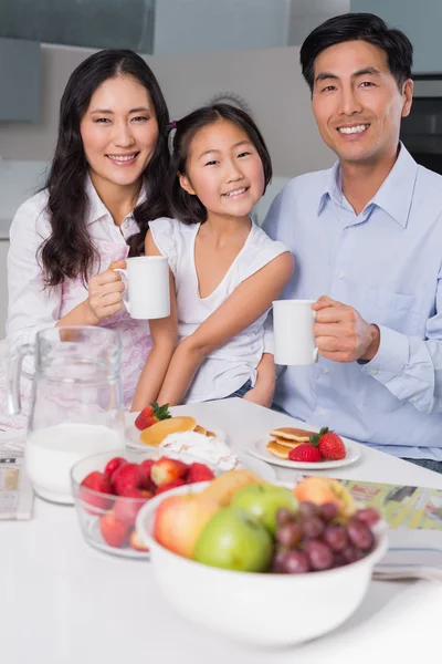 Retrato de una joven feliz disfrutando del desayuno con los padres — Foto de Stock