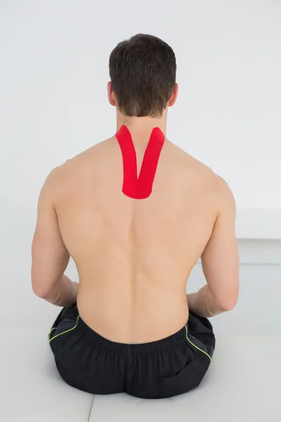 Visão traseira de um homem sem camisa com fita cinesio nas costas — Fotografia de Stock