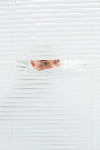 Close-up de um homem de negócios espreitando cortinas — Fotografia de Stock