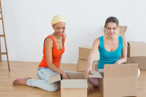 Happy friends unwrapping boxes in a new house — Stock Photo, Image