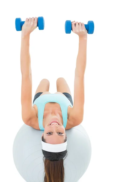 Fit woman exercising with dumbbells on fitness ball — Stock Photo, Image