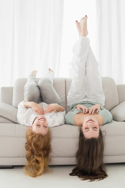 Amigos femininos deitados no sofá na sala de estar — Fotografia de Stock