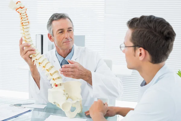 Médico explicando la columna vertebral a un paciente en el consultorio — Foto de Stock