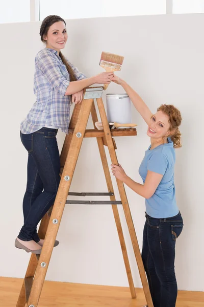 Vrienden met penseel en kunt u op de ladder in een nieuw huis — Stockfoto