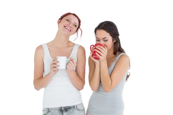 Две улыбающиеся девушки пьют кофе. — стоковое фото