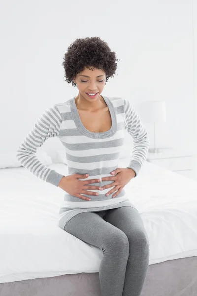 Donna casual con mal di stomaco seduta a letto — Foto Stock