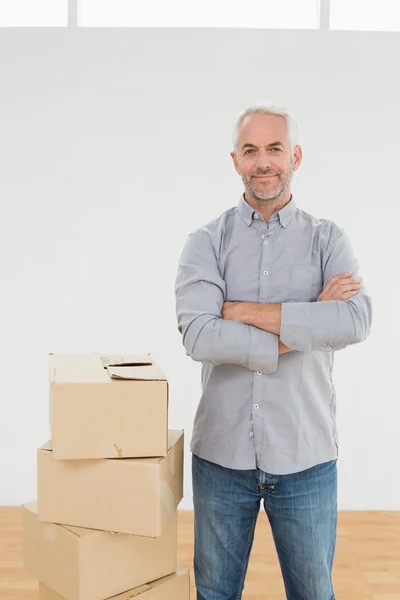 Sorridente uomo maturo con scatole in una nuova casa — Foto Stock