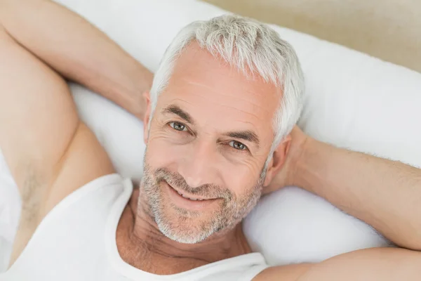 Close-up of a smiling mature man resting in bed — Stock Photo, Image