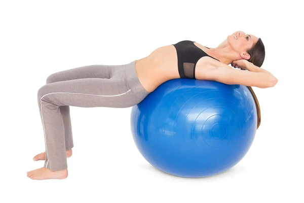 Vista lateral de una mujer en forma estirándose en la pelota de fitness —  Fotos de Stock