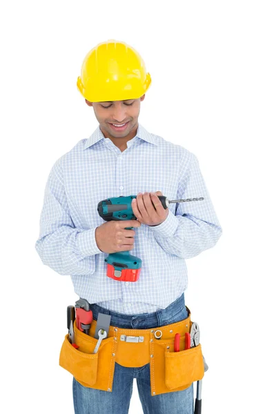 Sorrindo bonito jovem faz-tudo olhando para broca — Fotografia de Stock