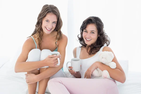 ベッドの中でコーヒー カップと女性の友達に笑顔 — ストック写真
