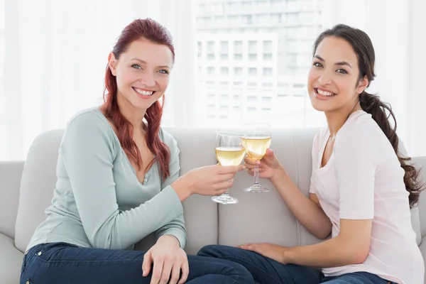 Two happy young female friends toasting wine glasses at home — Stock Photo, Image