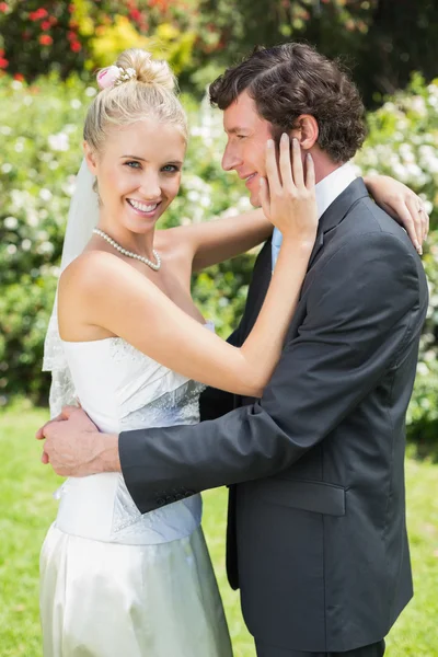 Mulher bonita tocando seu novo marido bochecha sorrindo para a câmera — Fotografia de Stock