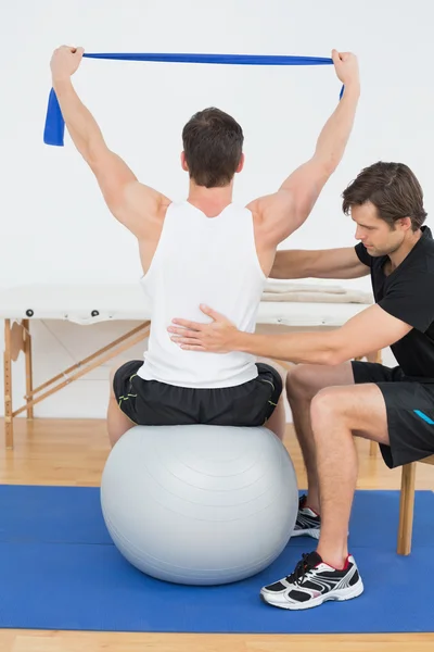 Man on yoga ball working with a physical therapist — Stock Photo, Image