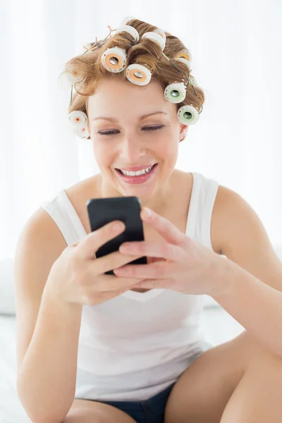 Žena v vlasy natáčky textových zpráv na posteli — Stock fotografie