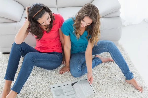 Female friends reading a book in the living room — Stock Photo, Image