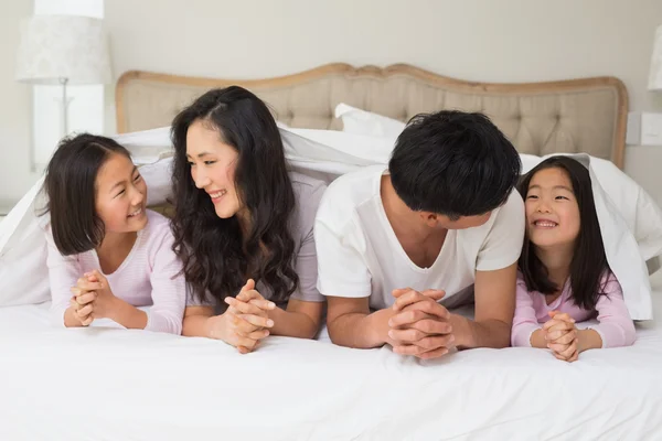 Glad familj på fyra i sängen — Stockfoto