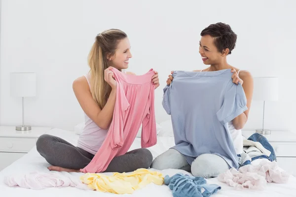 Belle amiche che selezionano i vestiti a letto — Foto Stock