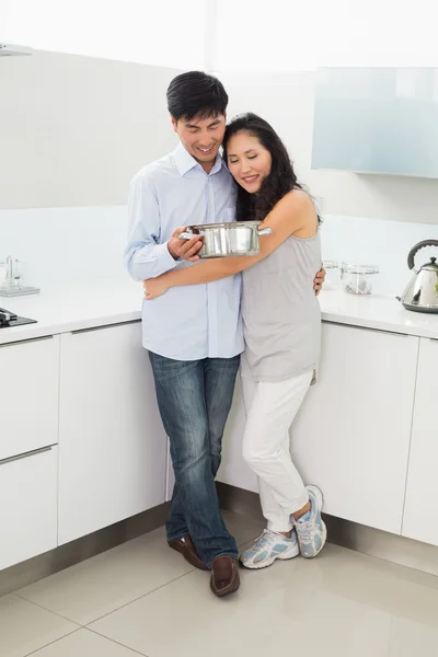 Longitud completa de una mujer abrazando al hombre en la cocina —  Fotos de Stock