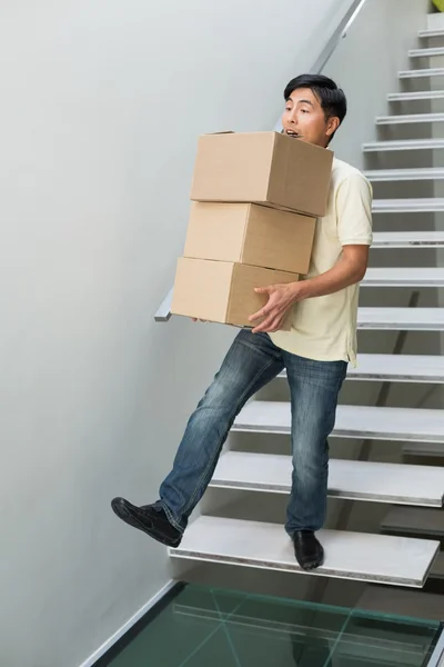 Mladý muž nesoucí boxy proti schodiště — Stock fotografie