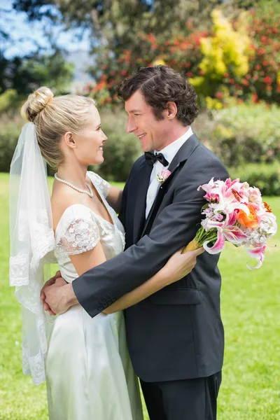 Braut und Bräutigam umarmen und lächeln einander an — Stockfoto