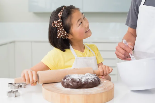 小女孩微笑着与她的父亲准备在厨房里的饼干 — 图库照片