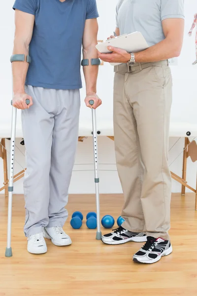 Male therapist and disabled patient with reports — Stock Photo, Image