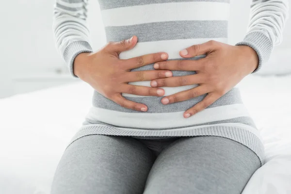 Partie médiane d'une femme souffrant de douleurs à l'estomac assise au lit — Photo