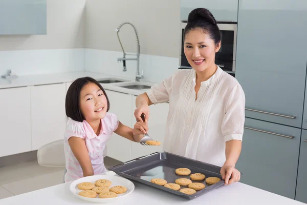 女の子彼女の母の台所でのクッキーの準備を助ける — ストック写真