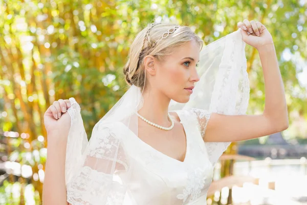 Content blonde bride holding her veil out