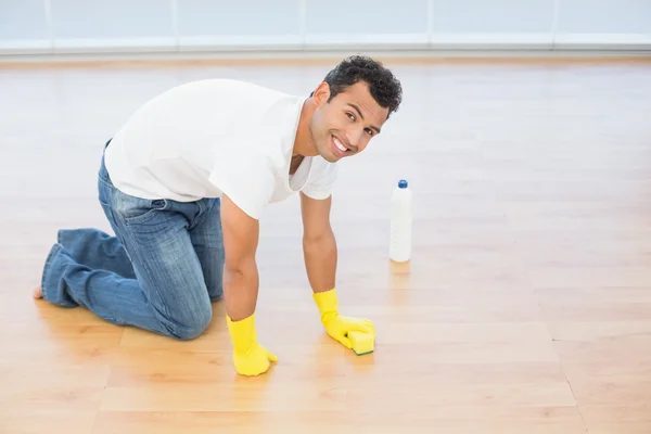 Sonriente joven limpiando el suelo de parquet en casa — Foto de Stock