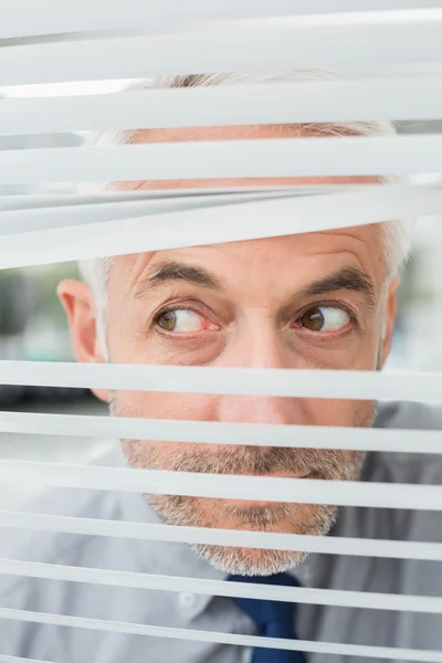 Close-up de um homem de negócios espreitando cortinas — Fotografia de Stock