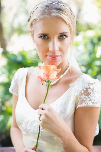 Sonriente novia rubia en collar de perlas sosteniendo rosa —  Fotos de Stock