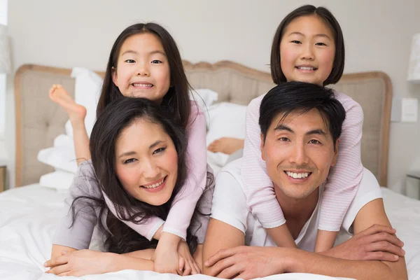 Loving family of four lying in bed at home — Stock Photo, Image