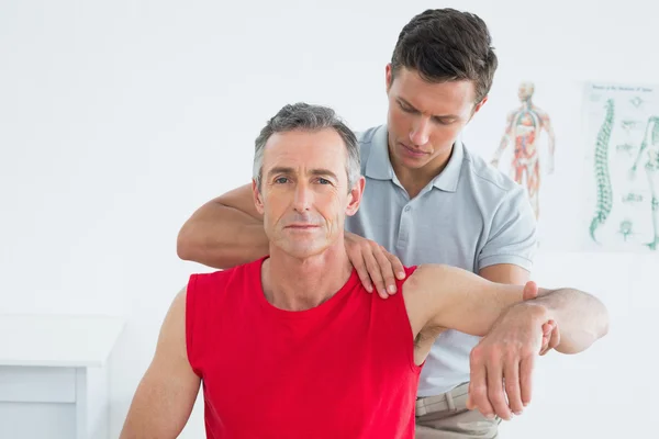 Fisioterapista maschio che allunga un braccio maturo di uomo — Foto Stock