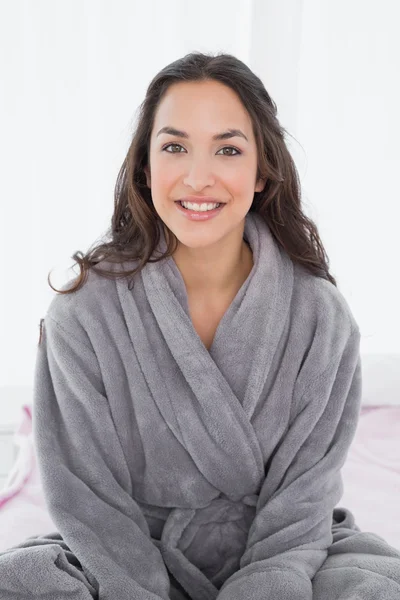 Retrato de uma jovem mulher de roupão sentado na cama — Fotografia de Stock