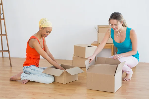 Happy friends unwrapping boxes in a new house — Stock Photo, Image