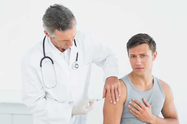 Médico varón inyectando un brazo de pacientes —  Fotos de Stock