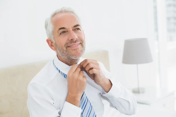 Mature businessman adjusting neck tie at home — Stock Photo, Image