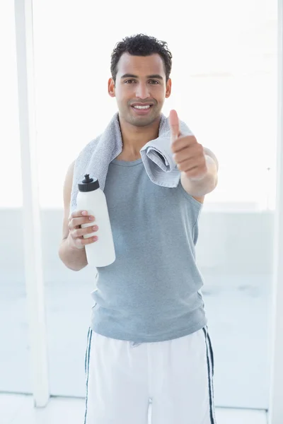 Mann mit Wasserflasche und Handtuch gestikuliert Daumen hoch im Fitnessstudio — Stockfoto