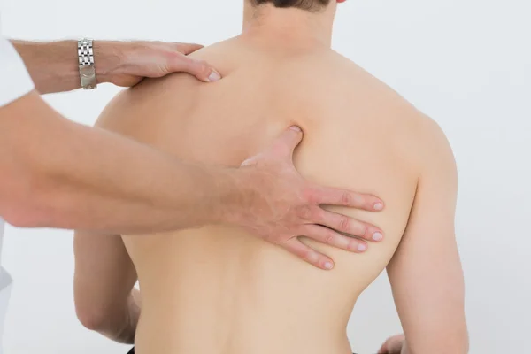 Vista trasera de un hombre siendo masajeado por un fisioterapeuta — Foto de Stock