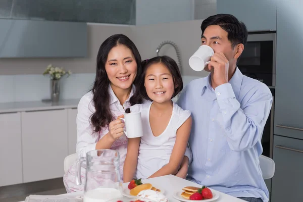 Portret van een gelukkig meisje genieten van ontbijt met ouders — Stockfoto