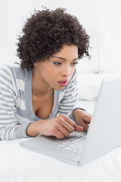 Primo piano di una donna seria che utilizza il computer portatile a letto — Foto Stock