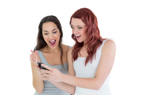 Wstrząśnięty koleżanki patrząc na telefon komórkowy — Zdjęcie stockowe